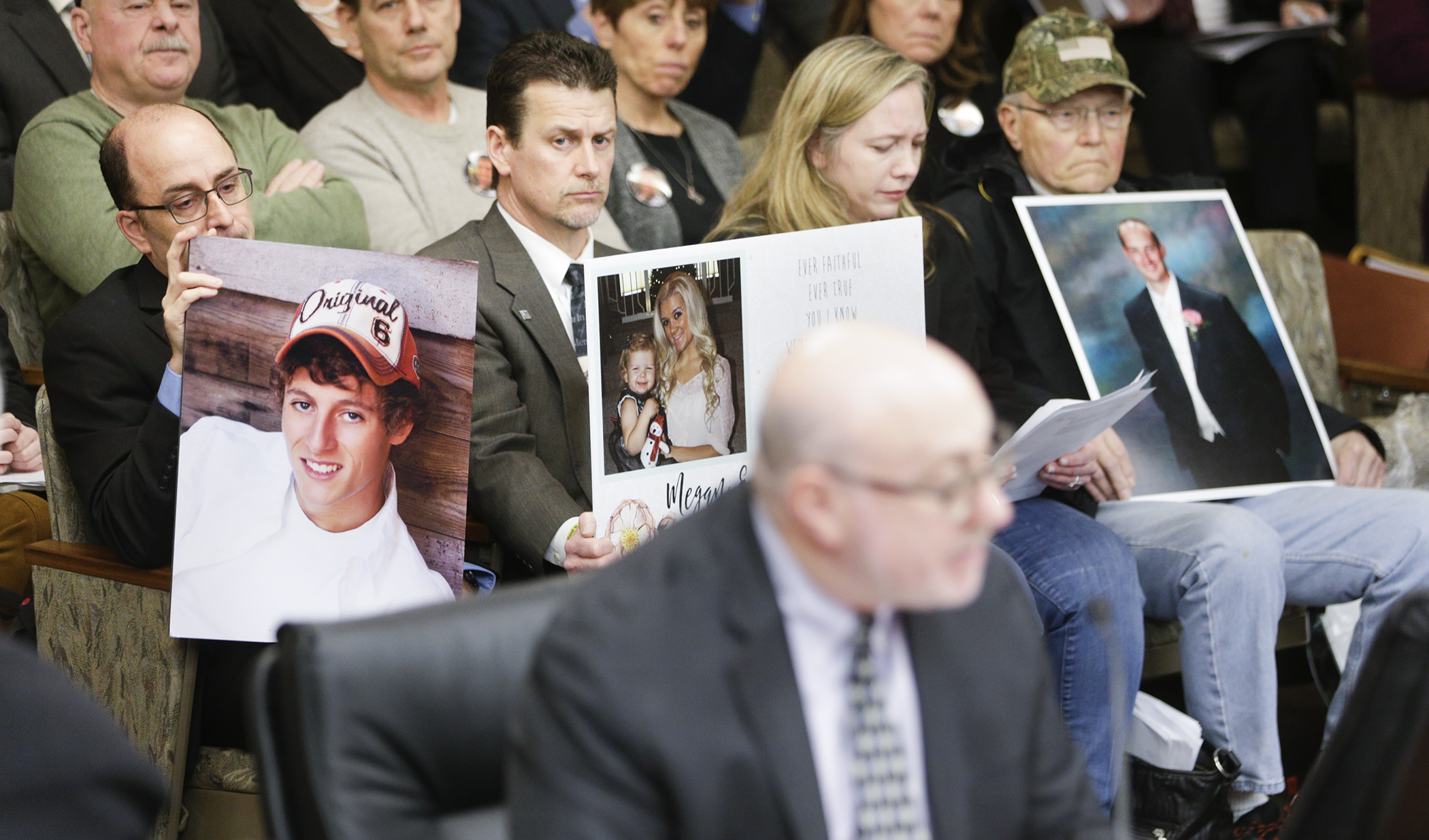 Audience members hold photographs of family members killed by distracted drivers as Rep. Frank Hornstein, foreground, begins his Jan. 22 testimony to the House Transportation Finance and Policy Division on HF50. Photo by Paul Battaglia
