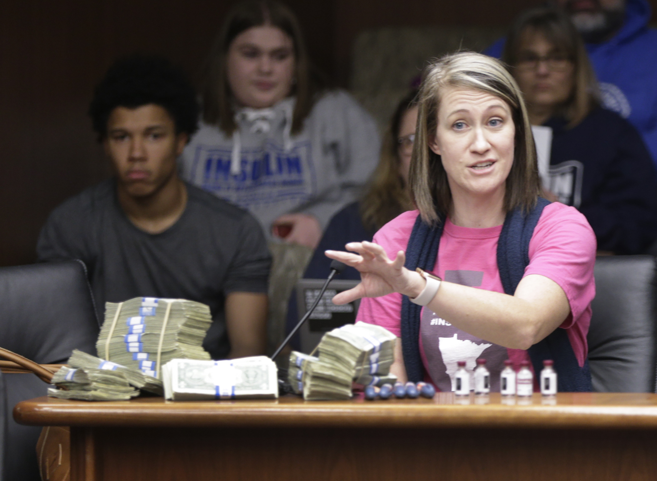 Shari Wiltrout, the mother of two type-one diabetic teenage daughters, displays a one month supply of their insulin, and the amount of cash that it costs, during her testimony on HF3100 in the House Commerce Committee Feb. 11. Photo by Paul Battaglia