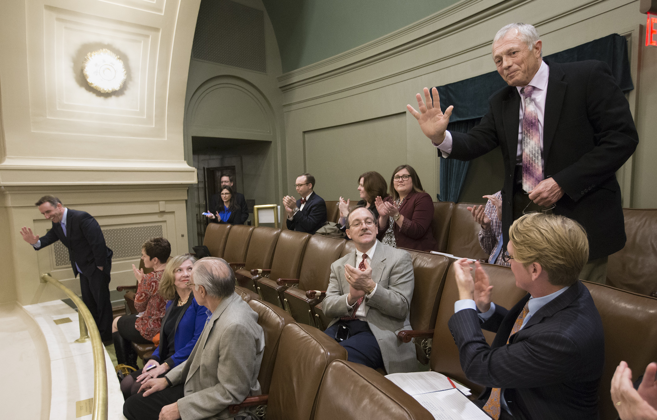 Former House Speaker Steve Sviggum, standing right, and Darrin Rosha, far left, wave from the House Gallery after being elected to the University of Minnesota Board of Regents Feb. 22. Photo by Paul Battaglia