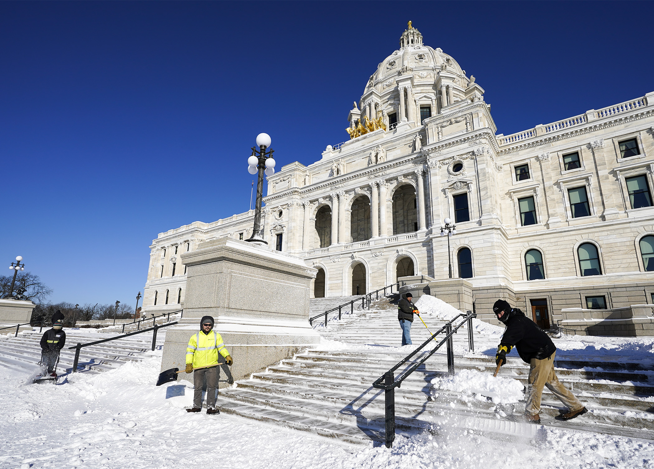 Members of the Department of Administration’s Plant Management grounds crew work to clear snow from the State Capitol steps on a frigid morning Feb. 23. Photo by Paul Battaglia