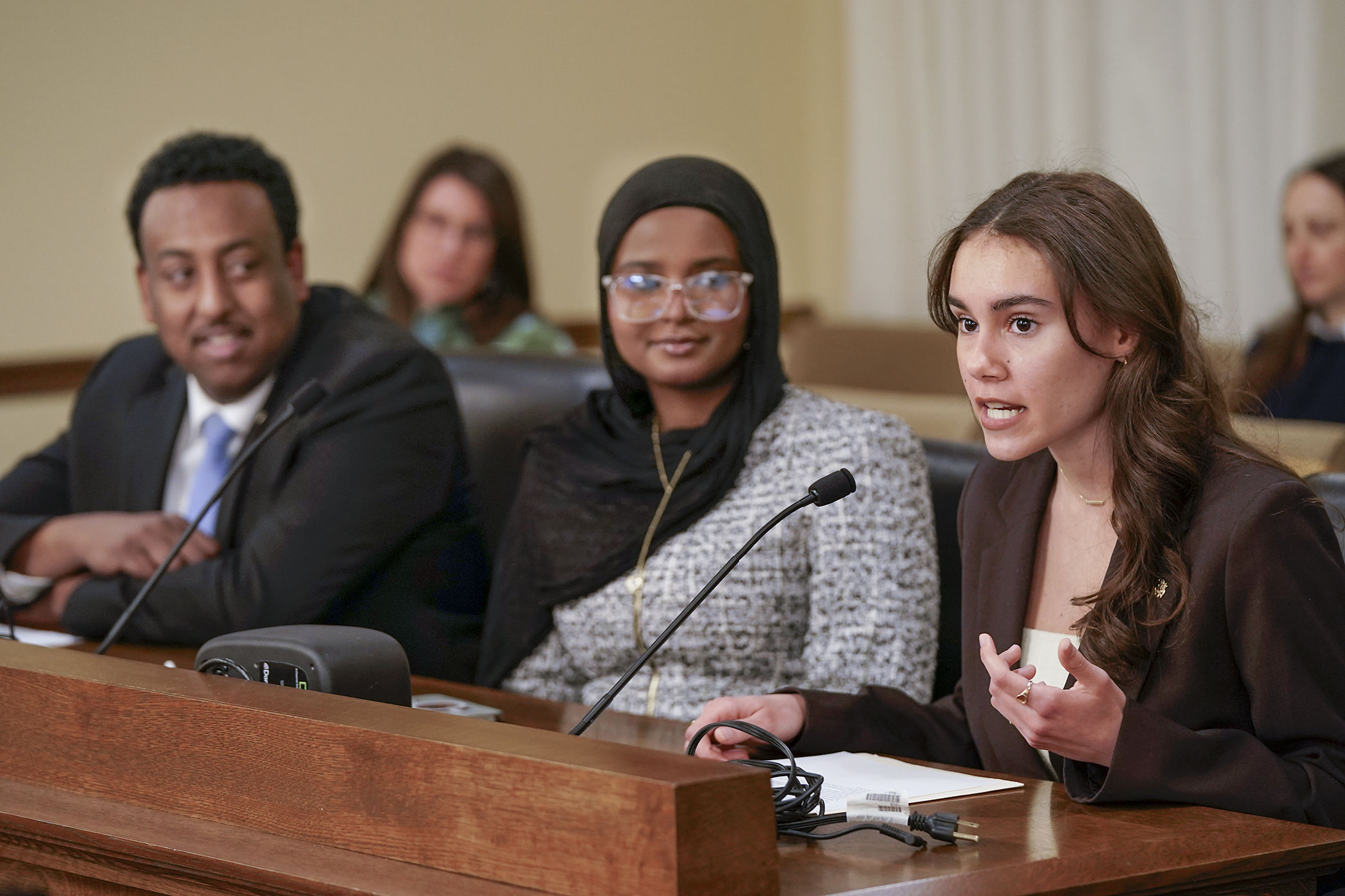 Maitreya Reeder testifies in support of HF3004 before the House Workforce, Labor, and Economic Development Finance and Policy Committee Feb. 25. The bill is sponsored by Rep. Samakab Hussein, left. Samia Mohamud also testified. (Photo by Michele Jokinen)