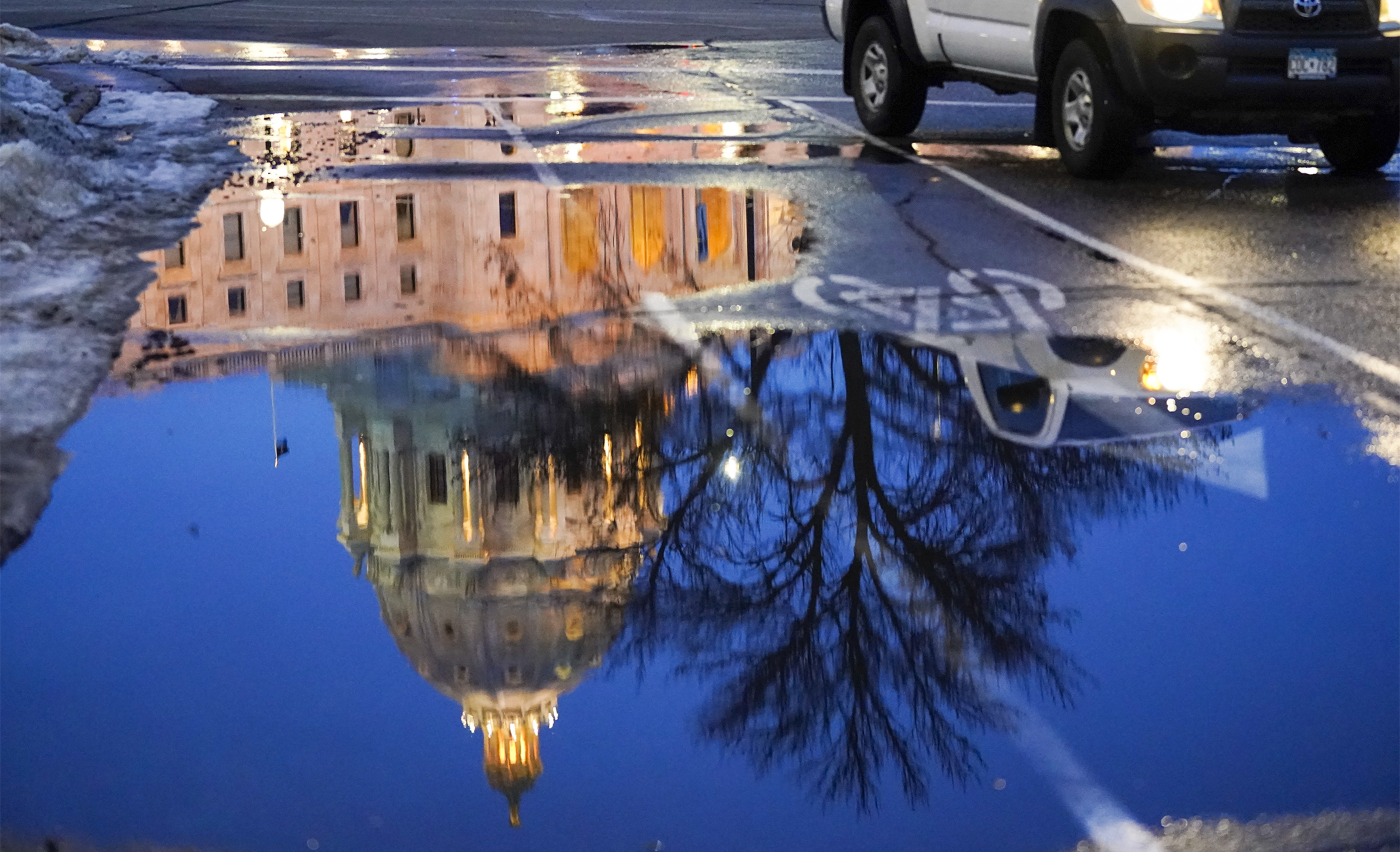 The State Capitol is reflected in a meltwater puddle the evening of Feb. 28, the last day of meteorological winter. (Photo by Paul Battaglia)