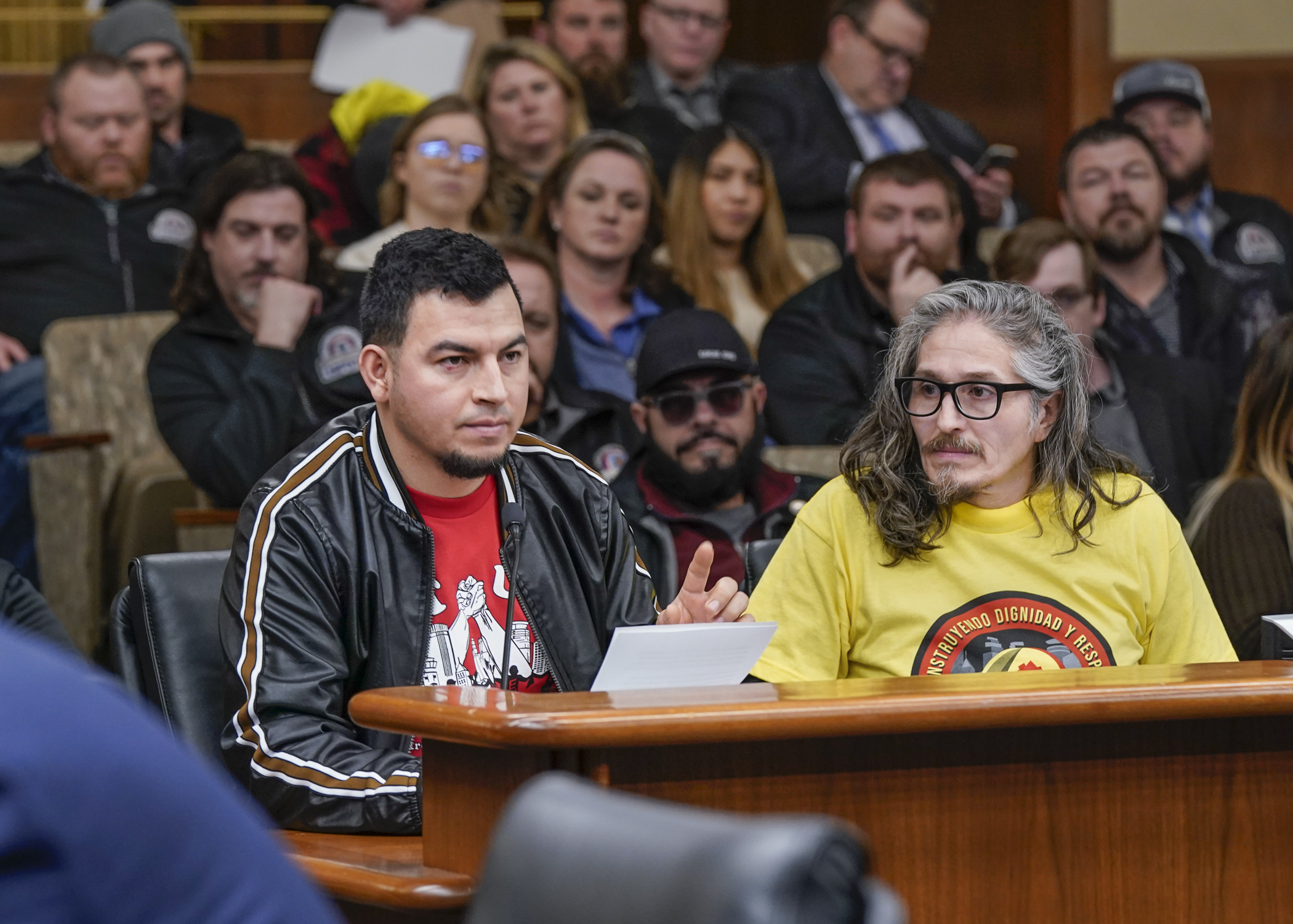 Alvaro Chavez testifies with the help of interpreter Carlos Garcia, right, before the House Labor and Industry Finance and Policy Committee in support of HF1859. (Photo by Catherine Davis)
