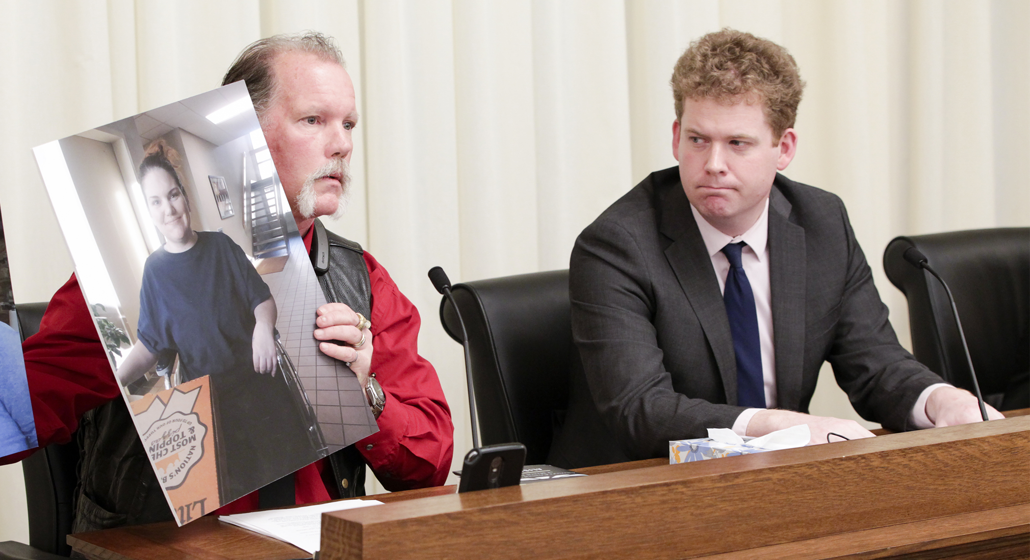Tim Barry holds a picture of his daughter Cassy as he testifies in the House Public Safety and Criminal Justice Reform Finance and Policy Division on HF474, sponsored by Rep. Zack Stephenson, right. Photo by Paul Battaglia