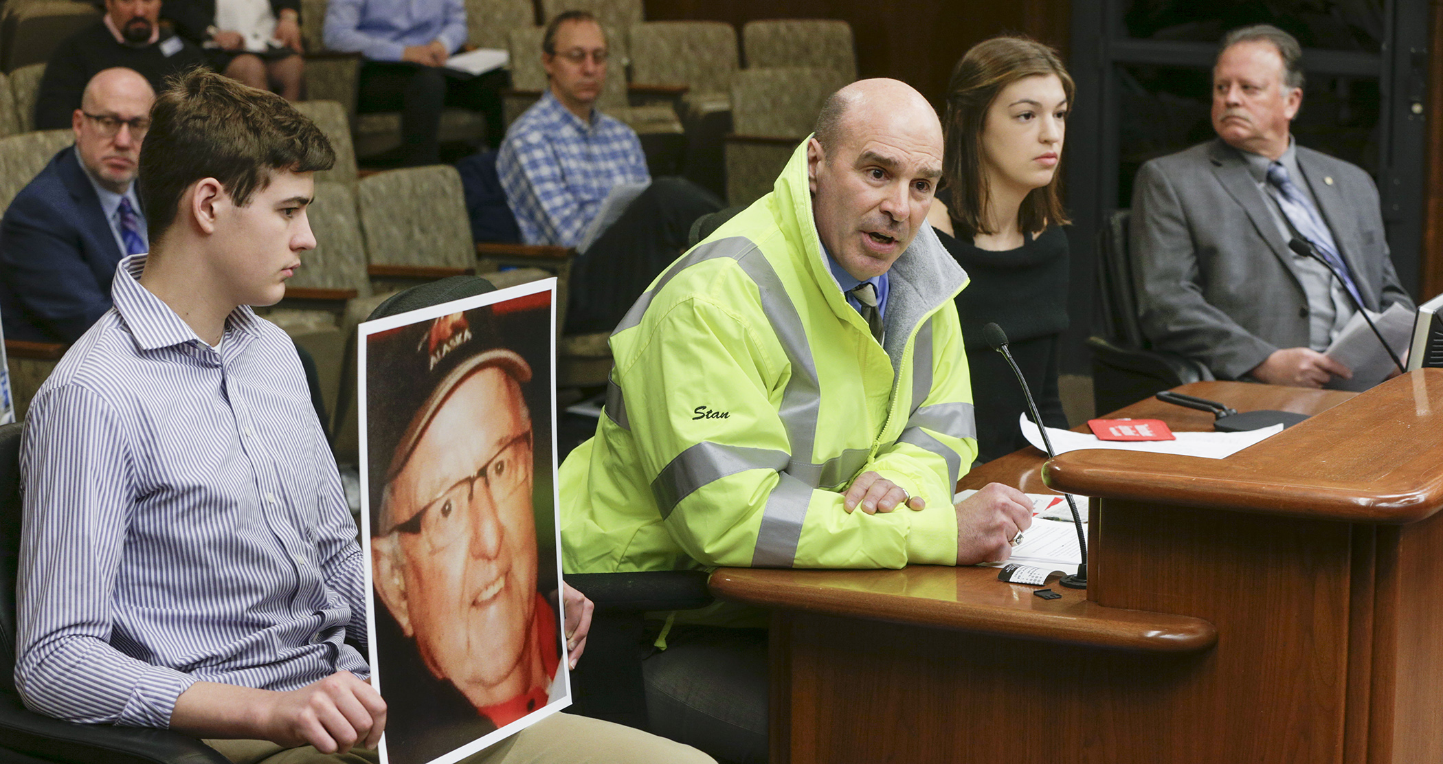 Greg Tikalsky tells the House Public Safety and Security Policy and Finance Committee how his father, Joe, was killed by a distracted driver. A bill sponsored by Rep. Mark Uglem, right, would require hands-free cell phone use. Photo by Paul Battaglia.