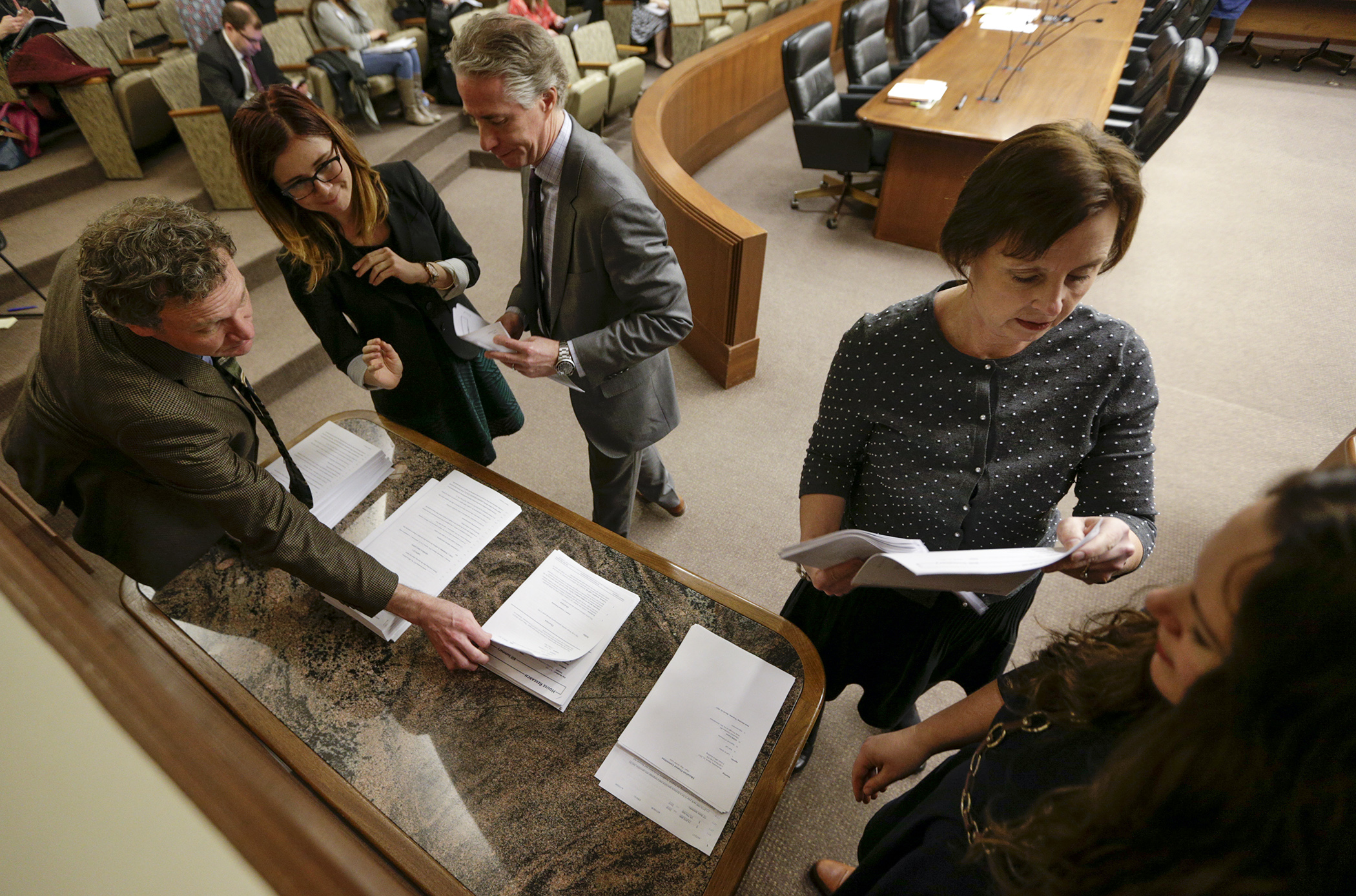 Lobbyists and other interested parties gather around a table March 22 to get copies of the omnibus education finance bill. Photo by Paul Battaglia