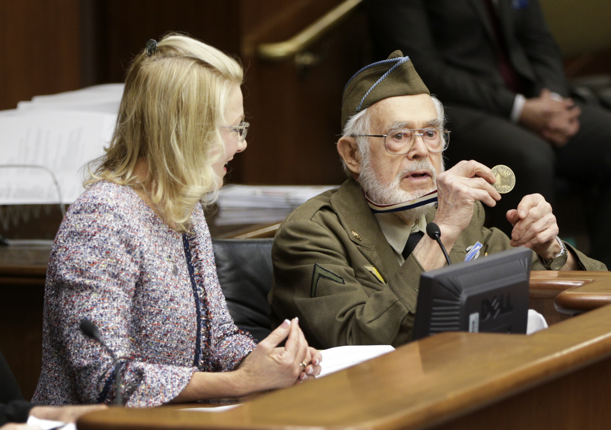 Word War II veteran Fremont Gruss shows members of the House Veterans Affairs Division the commemorative ribbon and medallion he received as part of the dedication of the World War II memorial on the Capitol Mall. He testified on HF4225, sponsored by Rep. Cindy Pugh, left, which would provide a similar commemorative medal to veterans of the Korean War. Photo by Paul Battaglia