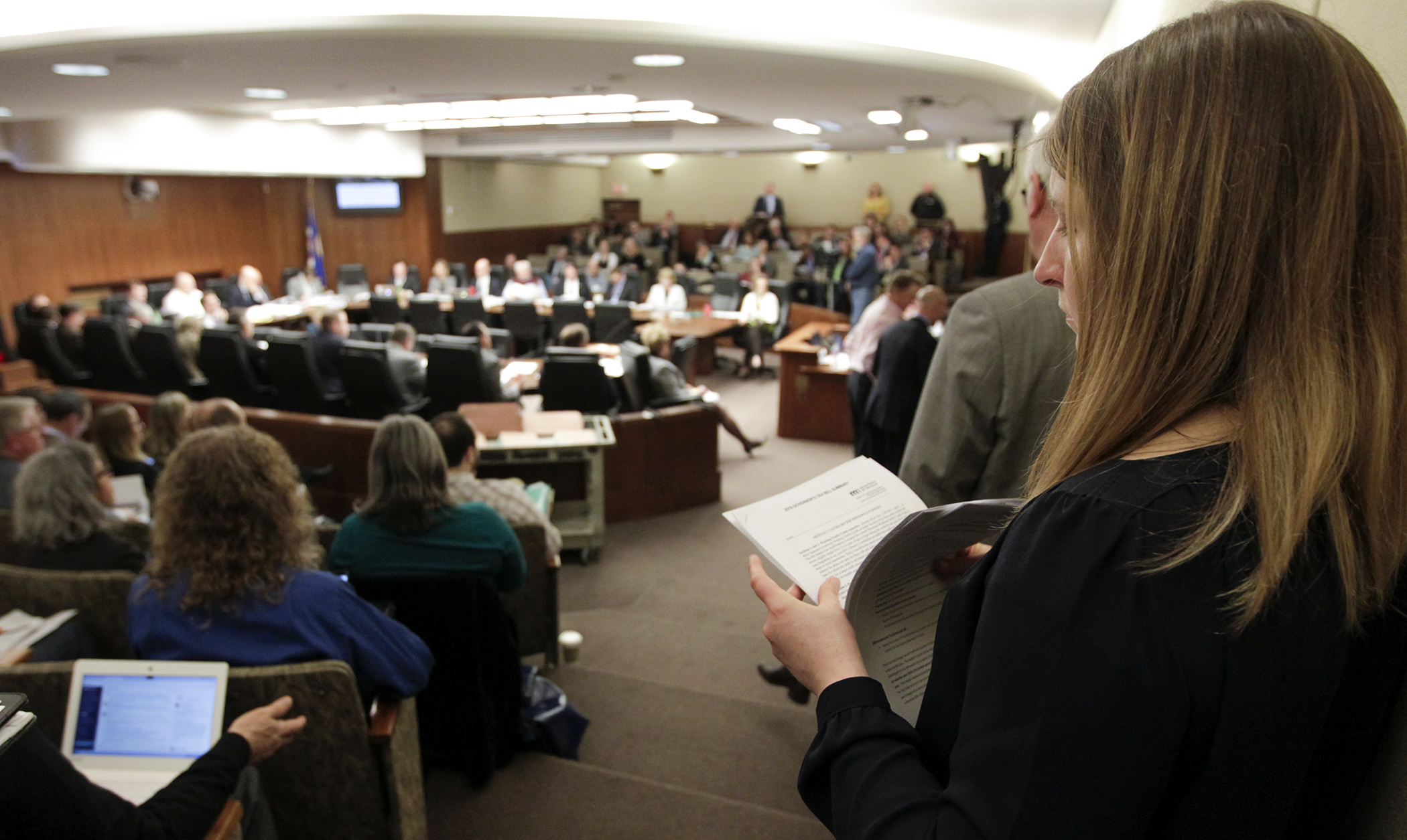 A member of the public looks through documents as the House Taxes Committee reviews HF4385, the governor’s tax proposal, during Tuesday’s hearing. Photo by Paul Battaglia