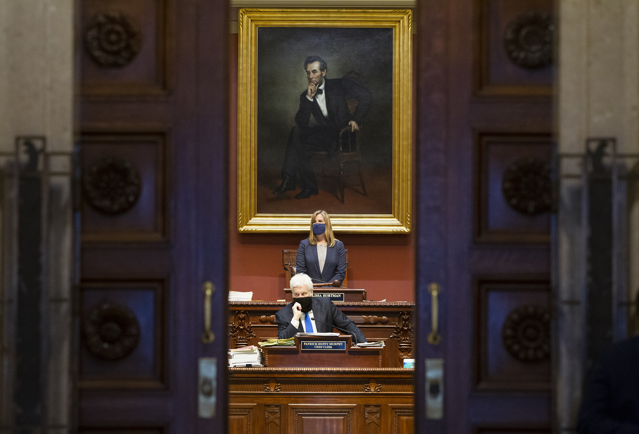 House Speaker Melissa Hortman and Chief Clerk Pat Murphy — viewed from outside the House Chamber — work during floor session April 21. Photo by Paul Battaglia