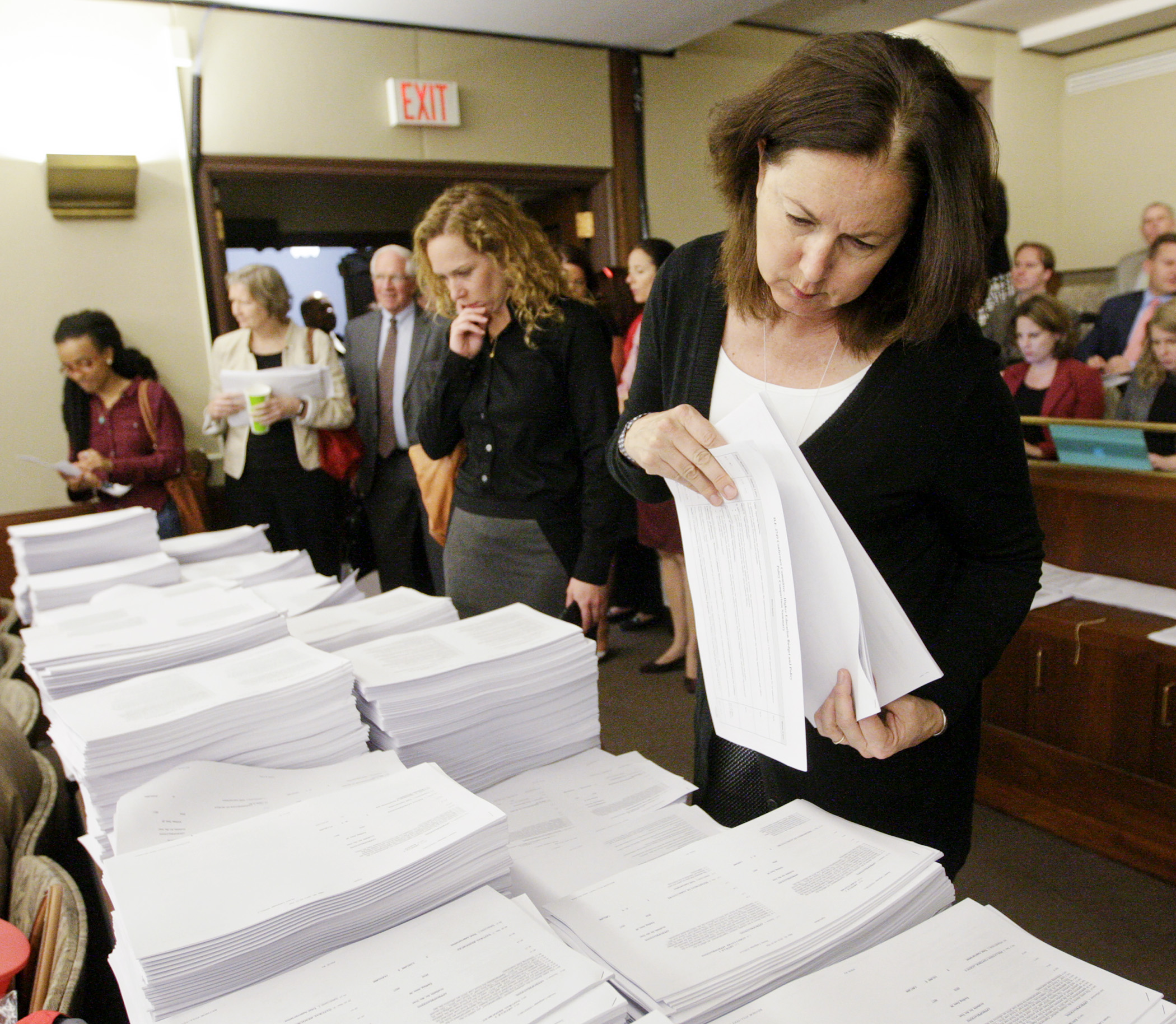 Lobbyist Maureen Shaver looks over one of the large stacks of committee documents before the first meeting of the House-Senate supplemental budget conference committee May 9. Photo by Paul Battaglia