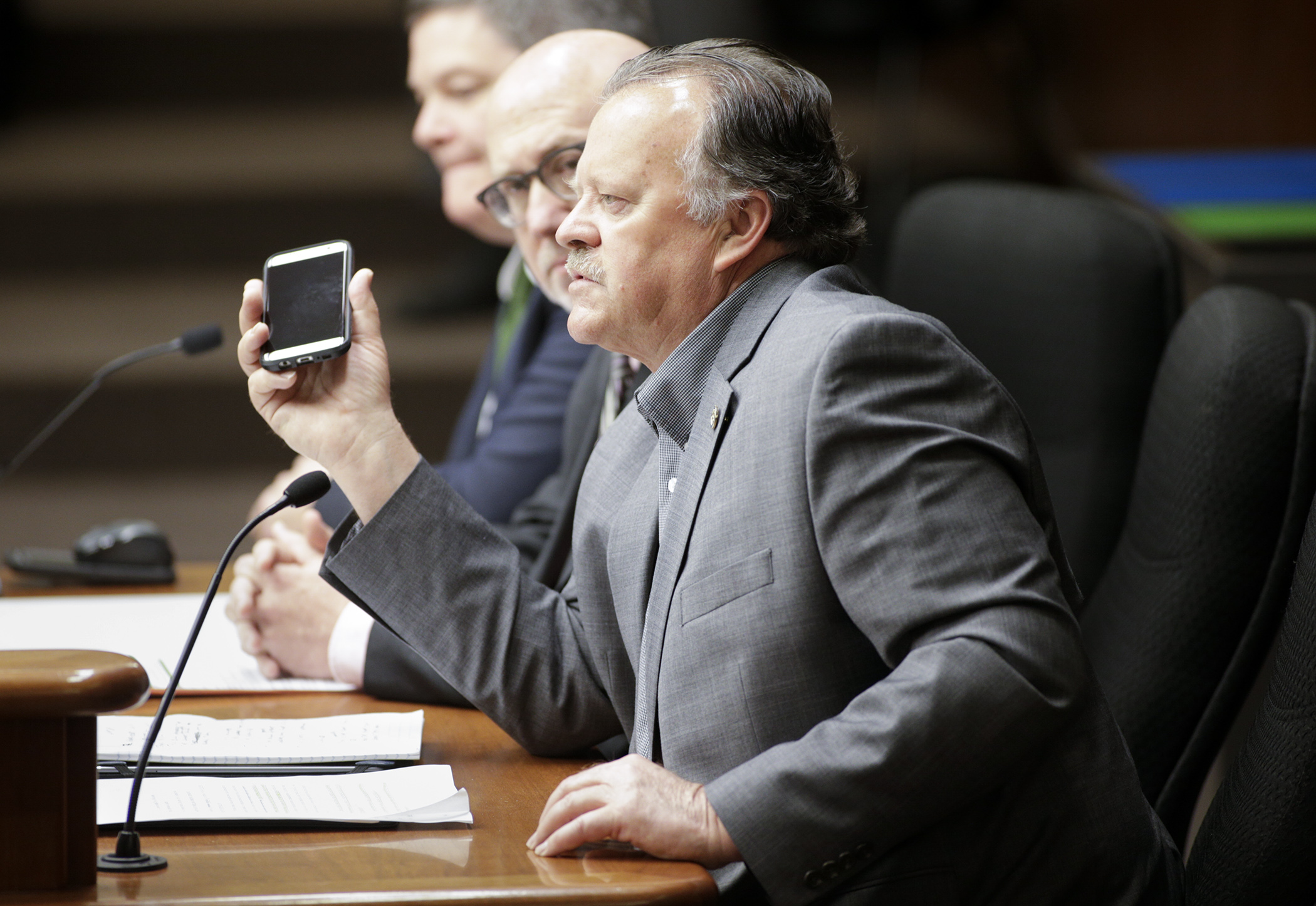 Rep. Mark Uglem holds a mobile phone while testifying May 10 in the House Ways and Means Committee on his bill HF1180, which would mandate hands-free cell phone use while driving. Photo by Paul Battaglia