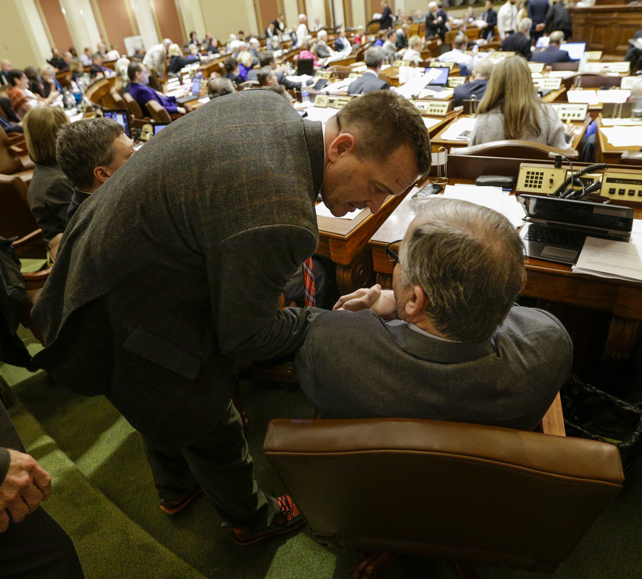 Rep. Bob Gunther, seated, chair of the House Legacy Funding Finance Committee, is congratulated by Rep. Leon Lillie after the passage of the omnibus legacy finance conference committee report May 21. Photo by Paul Battaglia