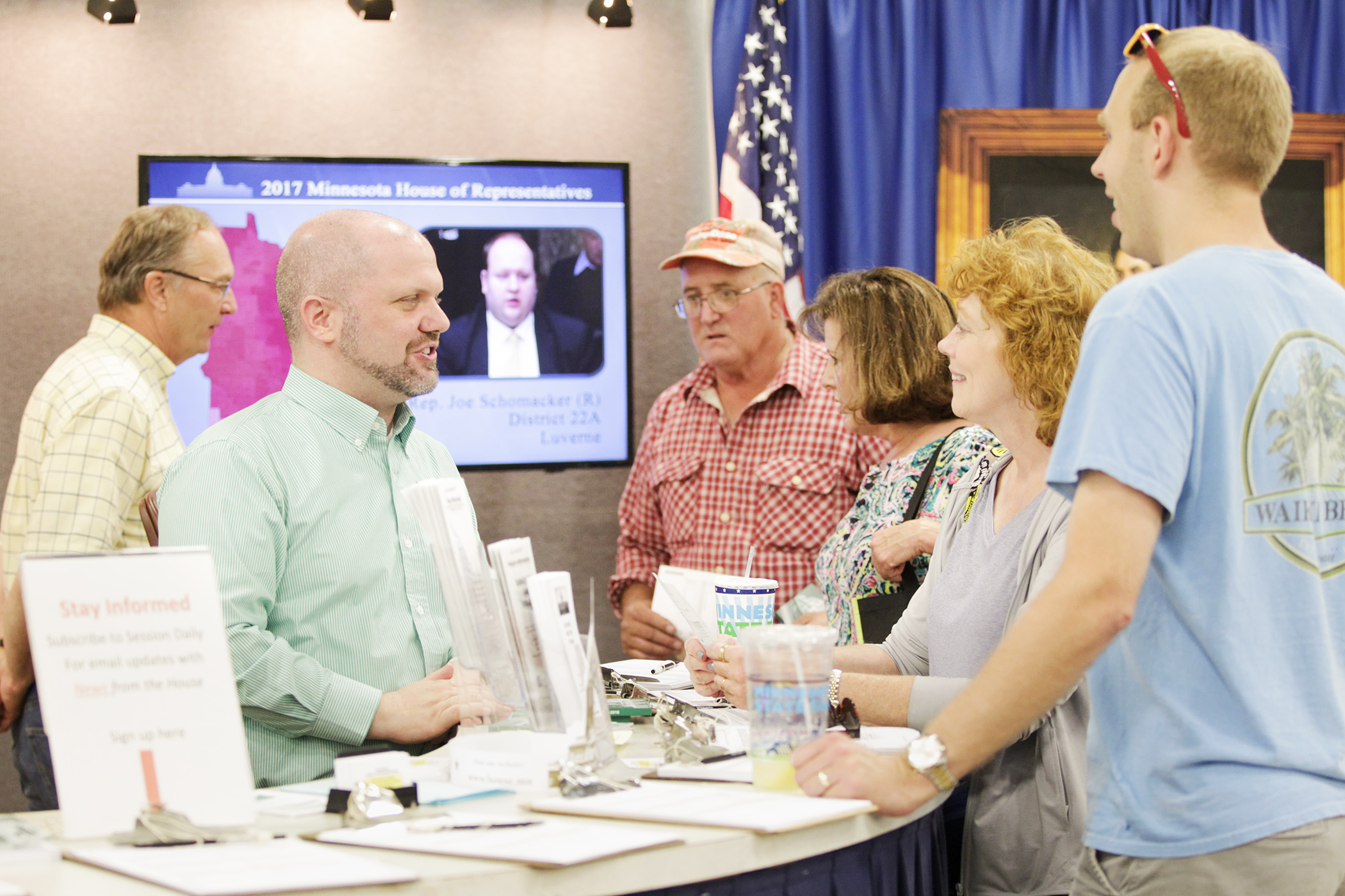 Rep. Mike Freiberg, second from left, and Rep. Paul Torkelson, behind, talk with visitors at the House booth during the 2017 state fair. Photo by Paul Battaglia