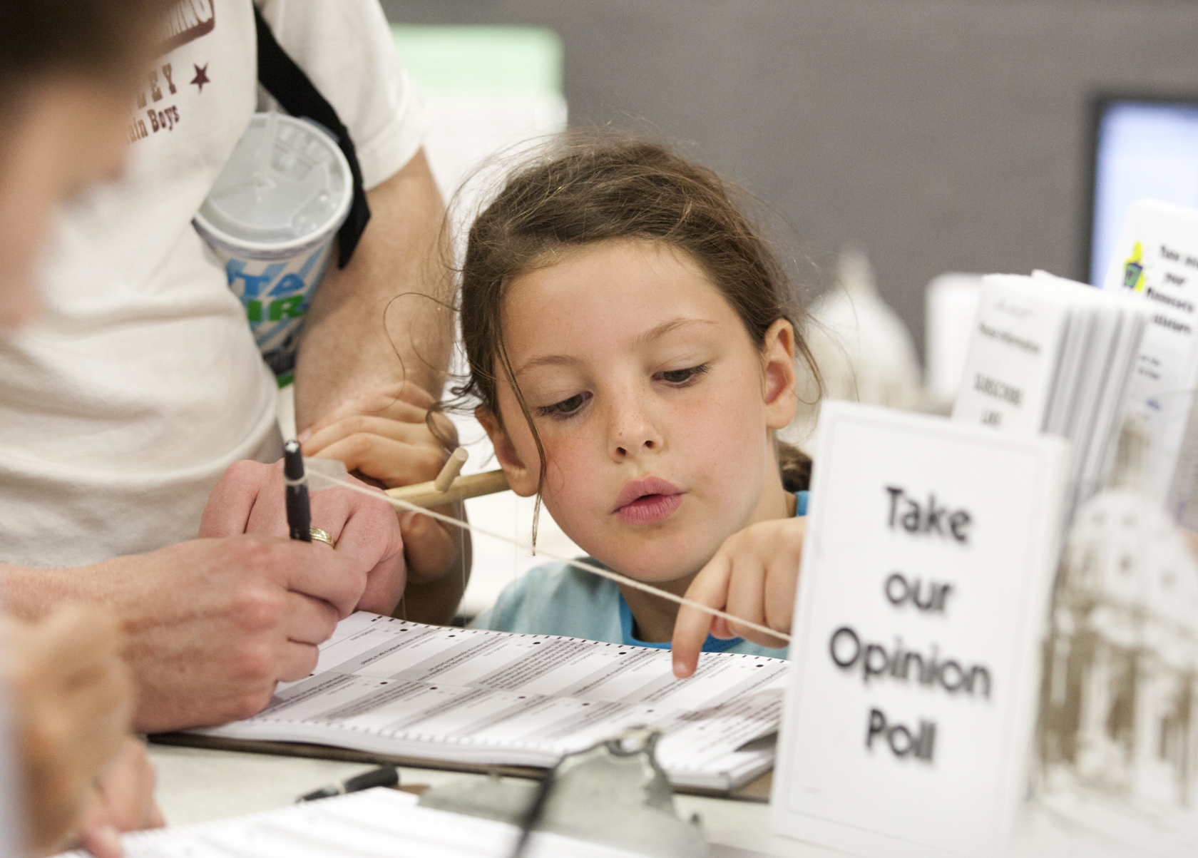 A young visitor checks over her dad's answers to the annual House opinion poll at the Minnesota State Fair. Photo by Paul Battaglia