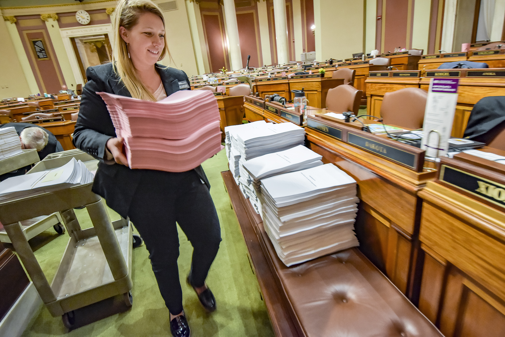 Cathy Carlson, administrative assistant for the Chief Clerk's Office, rolls out amendments to the omnibus health and human services finance bill during a late evening Session recess Wednesday. Photo by Andrew VonBank